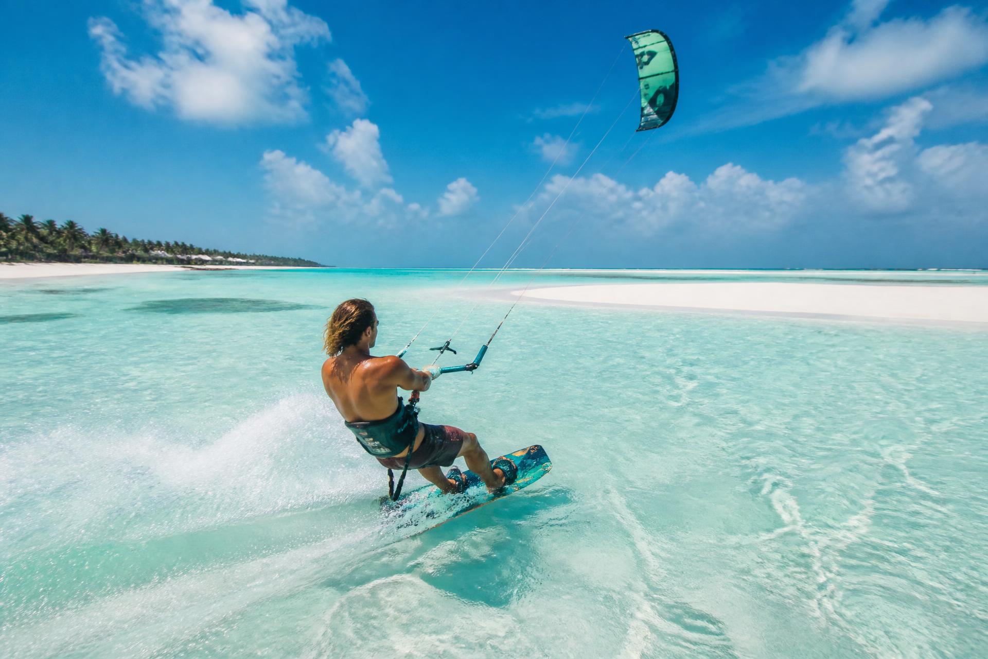 Kitesurfing in Paje, Zanzibar — rider crossing the flat turquoise lagoon beside the exposed sandbar
